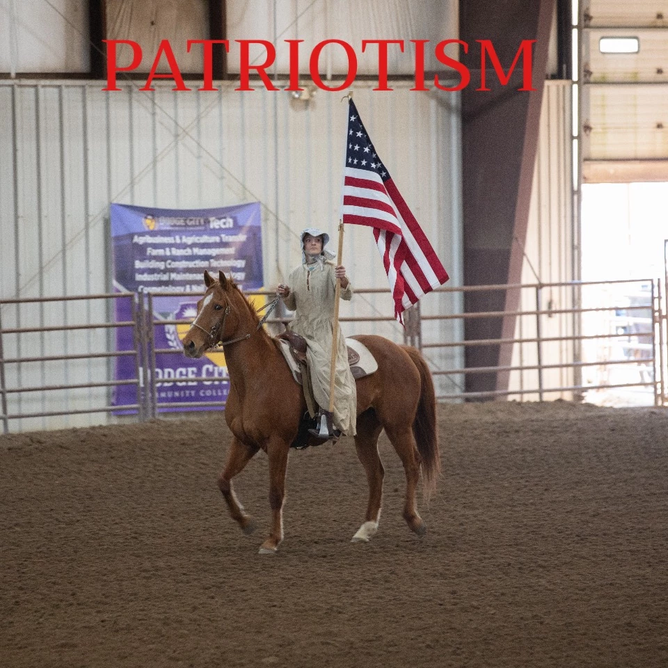 Rider carrying an American flag in a rodeo arena beneath the word Patriotism